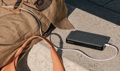 Power bank with cable plugged into smartphone which is resting on a bag