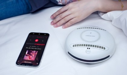 A small round white cool gadgets 2019 cleaning robot next to a child and a smartphone.