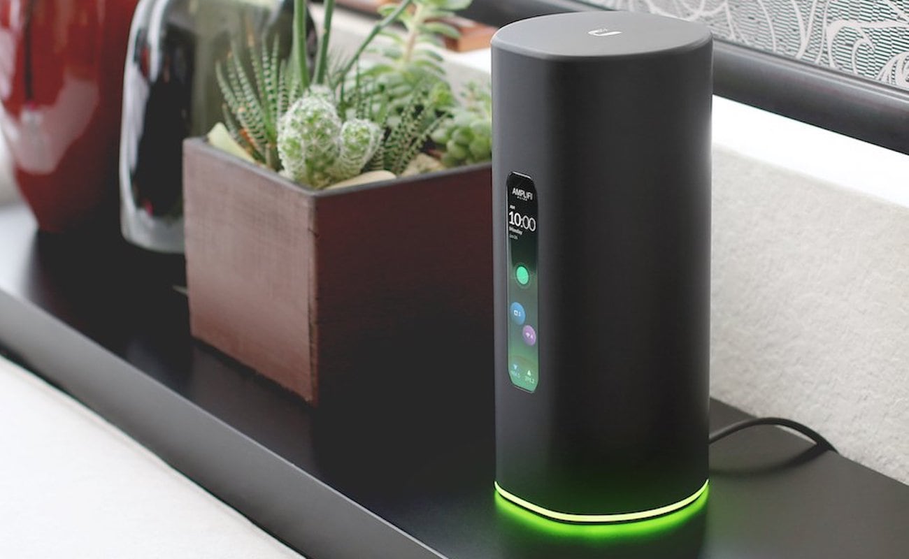 The tri-band wi-fi 6 router is on a table next to a plant.