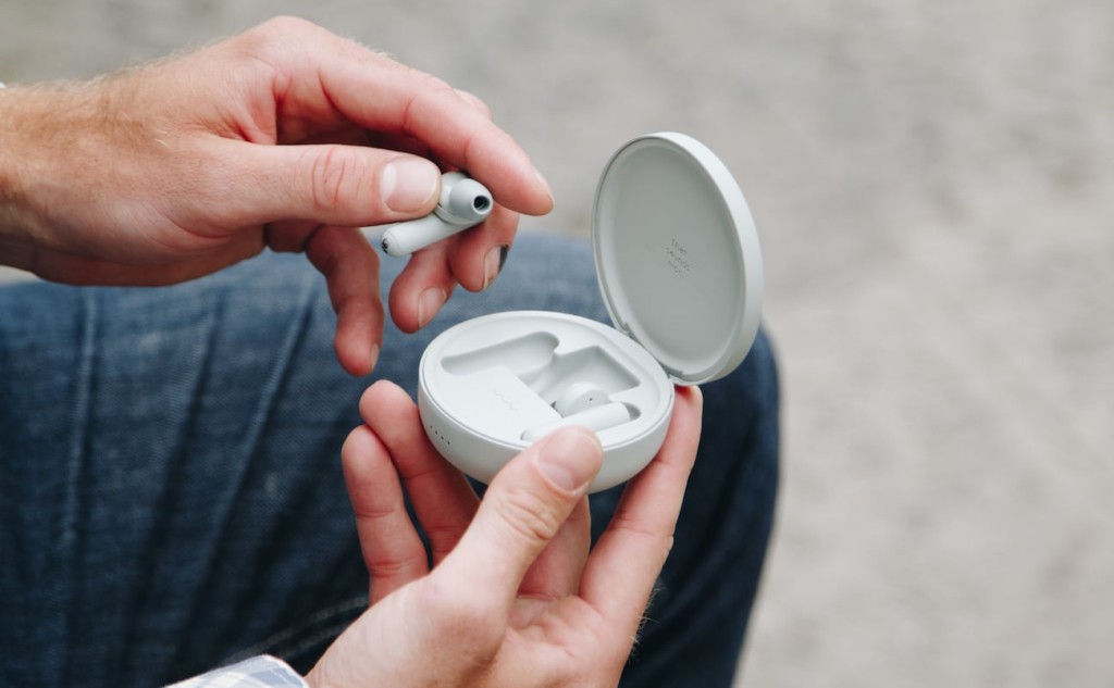 A person holding a case of comfortable earbuds and pulling one out.