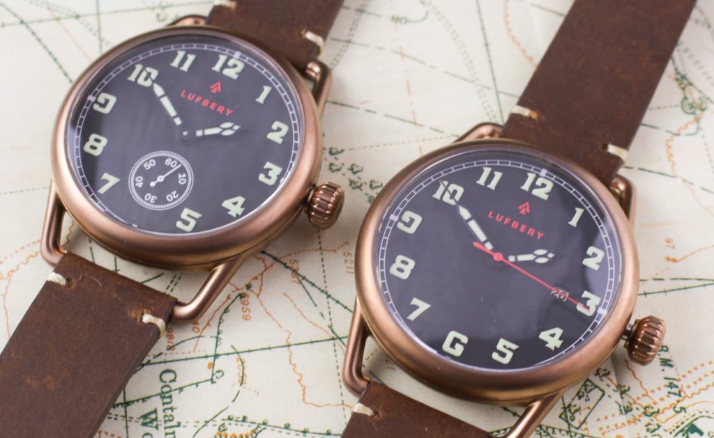 A pair of bronze trench watches with blue faces and brown leather bands, side by side, on top of a map