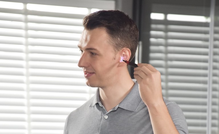 A man using a latest tech gadgets earwax remover.
