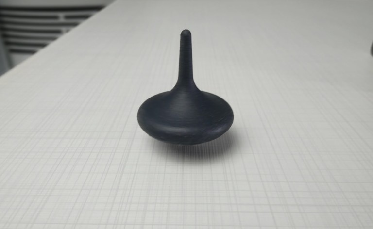 A black latest tech gadgets spinning top on a white table.