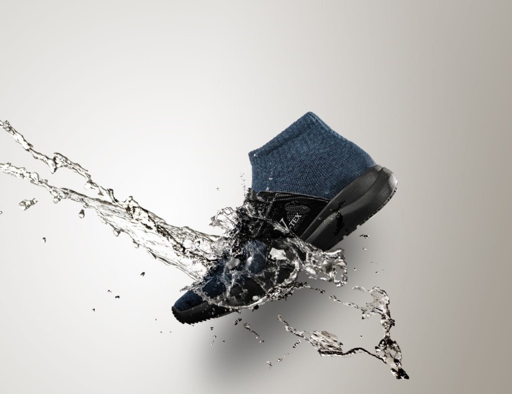 A black and blue high top waterproof shoes with a stream of water coming down on it.