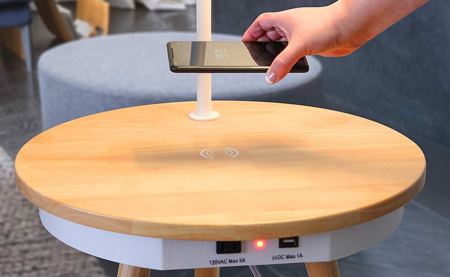 A hand is putting a smartphone on the lamp side table wireless charger.