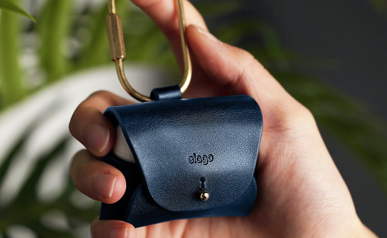 A hand is holding the blue mini earbud purse.