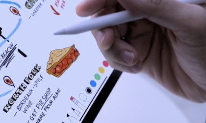 A person is holding an Apple Pencil and drawing on an iPad Pro.