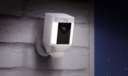 A security camera with lights is mounted on white bricks.